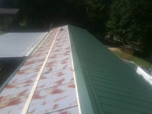 Old rusted panels beside newly installed green metal roofing — Wind Damage Roof Repair by Roofing Brothers in Bellbrook