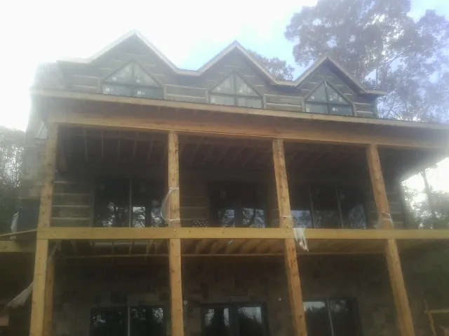 Dormers and porch framing on a large log home under construction — Roof Coating work by our crew in Bellbrook