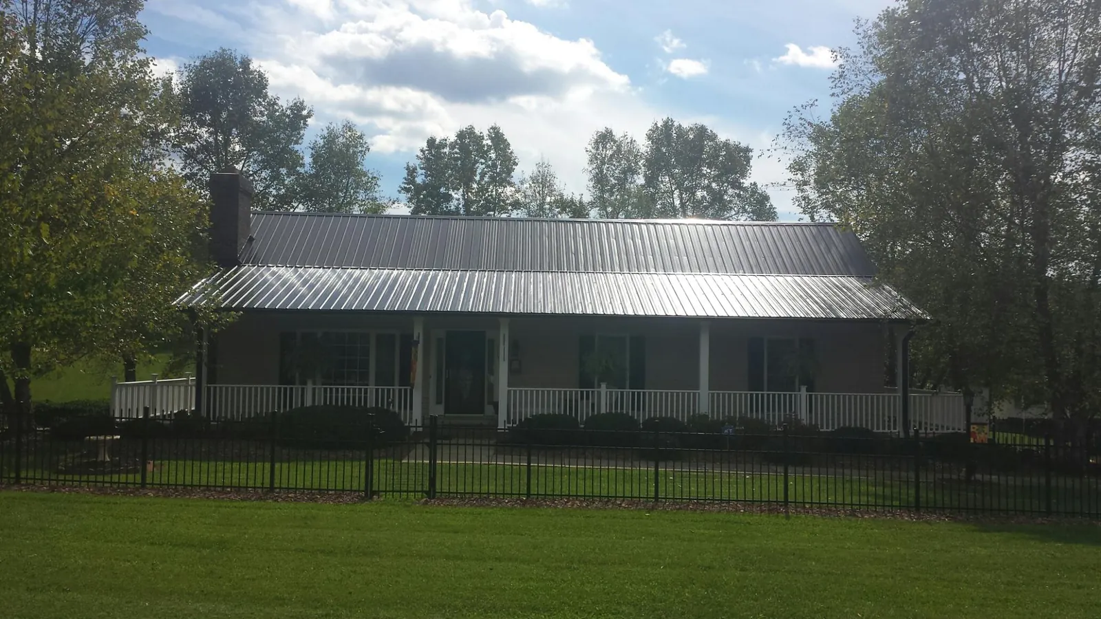 Gray metal roof on a brick ranch with a full width front porch — Gutter Guard Installation work by our crew in Bellbrook