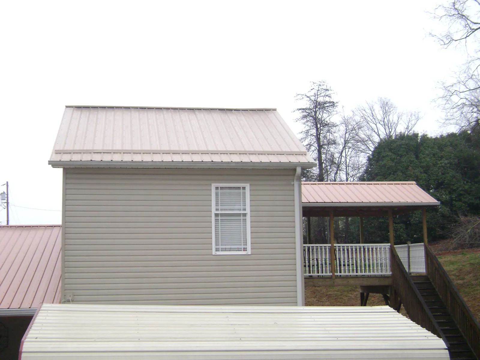 Tan metal roofs on a two story addition and attached porch, from a Roof Replacement job in Bellbrook