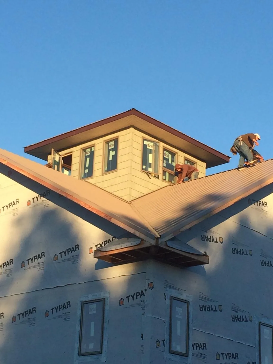 Roofers working around a rooftop cupola on a new metal roof at sunset — Roof Waterproofing in Bellbrook by Roofing Brothers